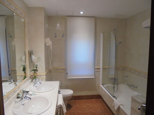 Une salle de bain avec deux lavabos, des toilettes, une douche et une baignoire.