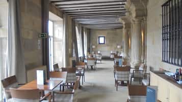 Un comedor amplio con techos altos, paredes de piedra y varios juegos de mesas y sillas.
