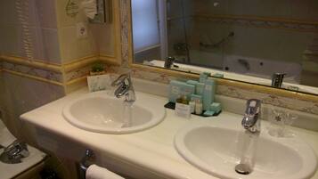 Une salle de bain avec deux lavabos, un miroir et un espace douche.