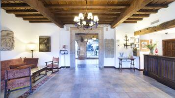 A lobby with a wooden ceiling, a chandelier, a reception desk, and a seating area with patterned chairs.