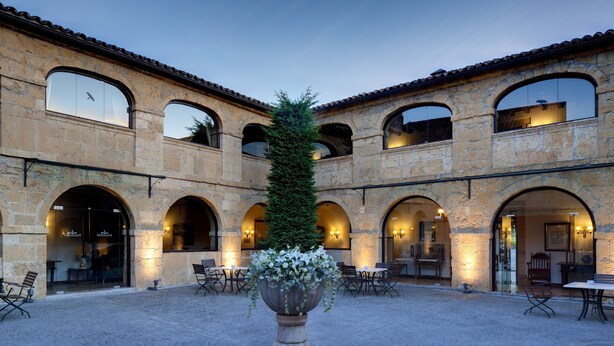 A courtyard with stone arches, a central planter with flowers, and outdoor seating. - Parador De Cangas De Onis (Cangas de Onis)