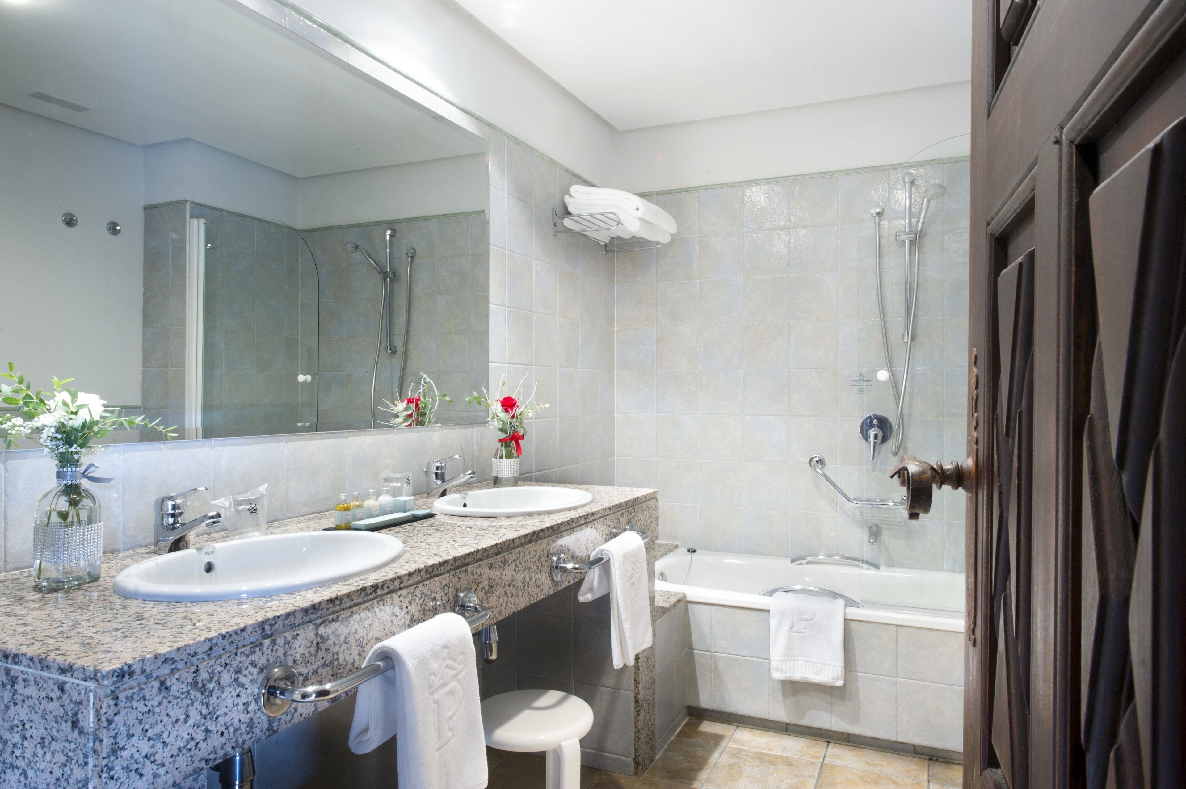 Un baño moderno con dos lavabos, un espejo grande, ducha y bañera.