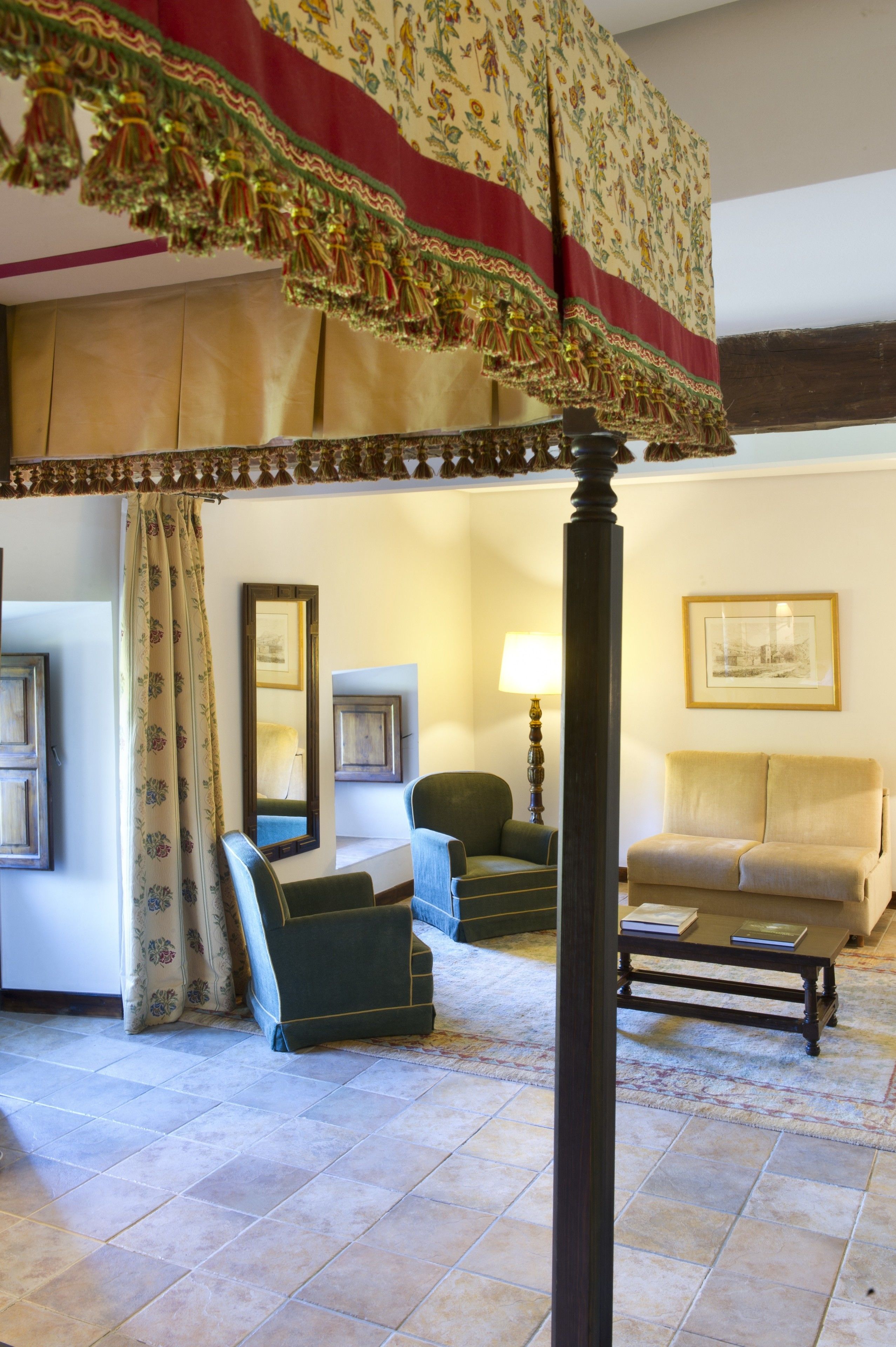 Une chambre avec un grand lit, deux chaises, une table et une lampe.