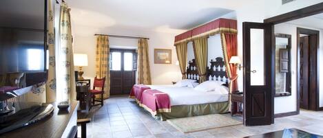 Habitación de hotel con cama, escritorio, silla, televisor y puerta.