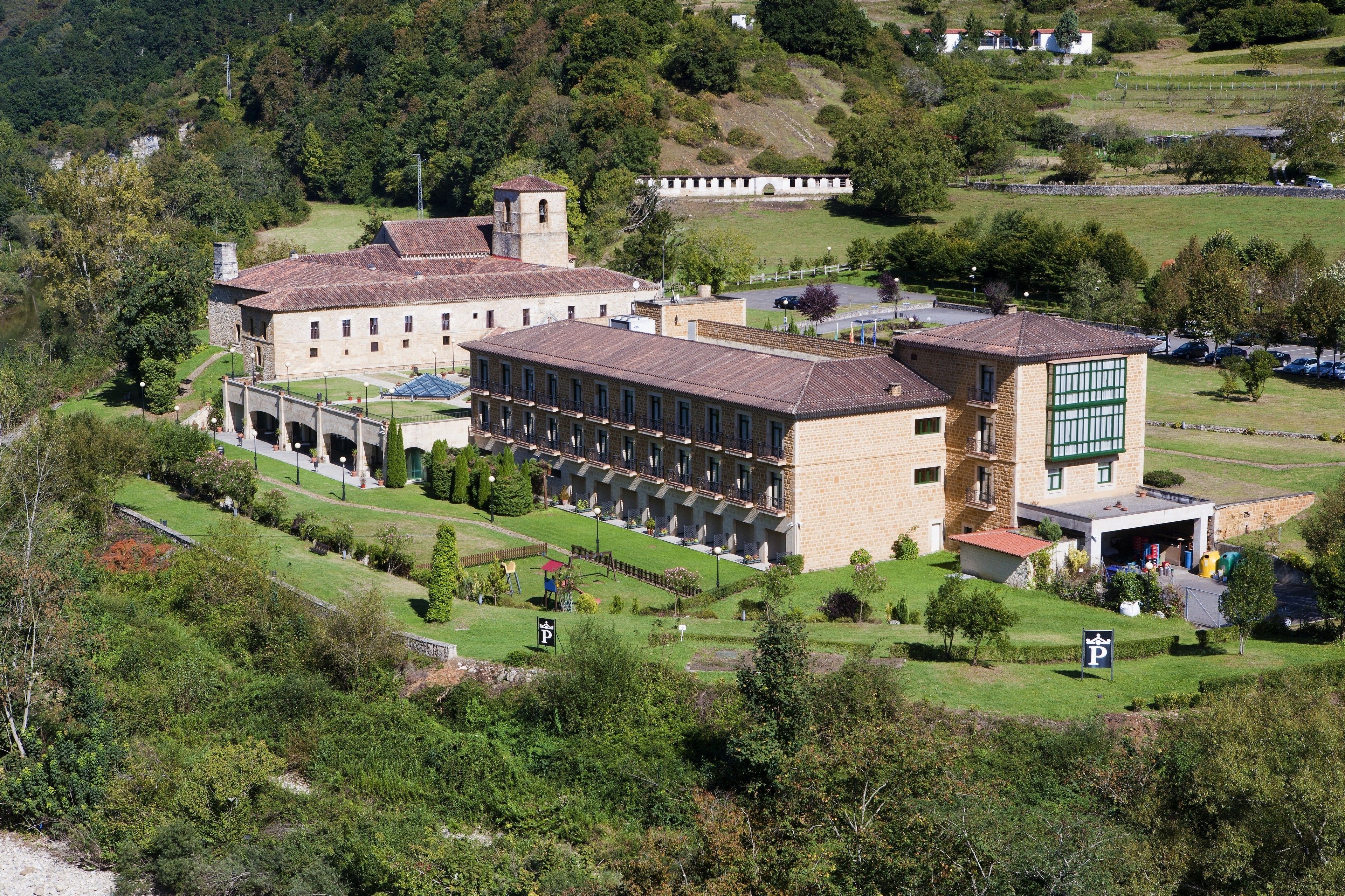 A large building with multiple wings, surrounded by green lawns and trees.