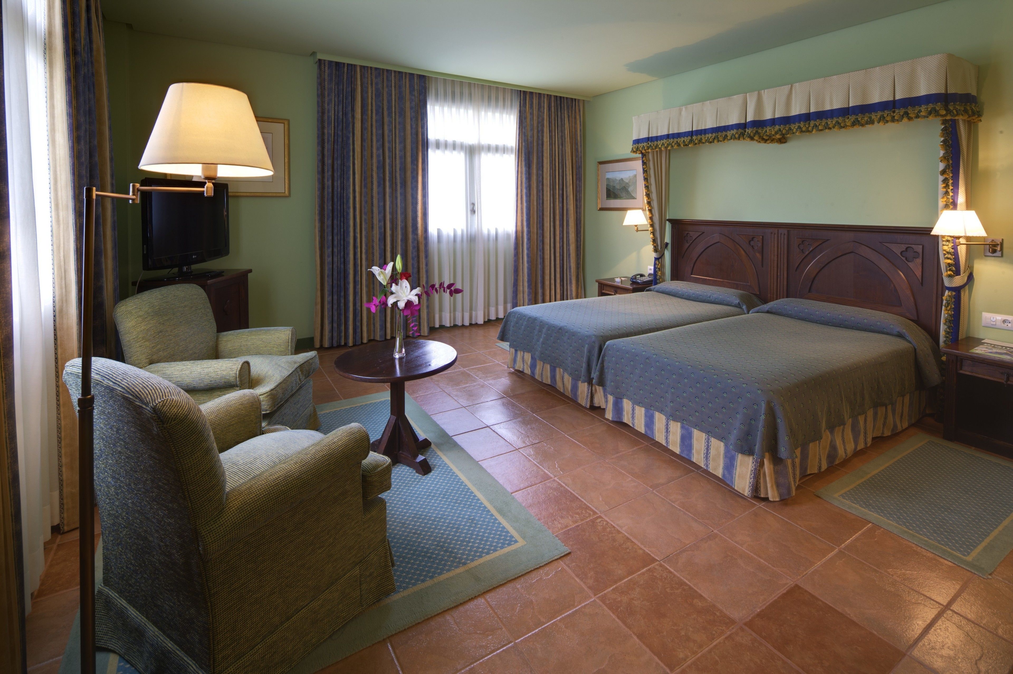 Habitación de hotel con dos camas, televisión, una silla y una mesa.