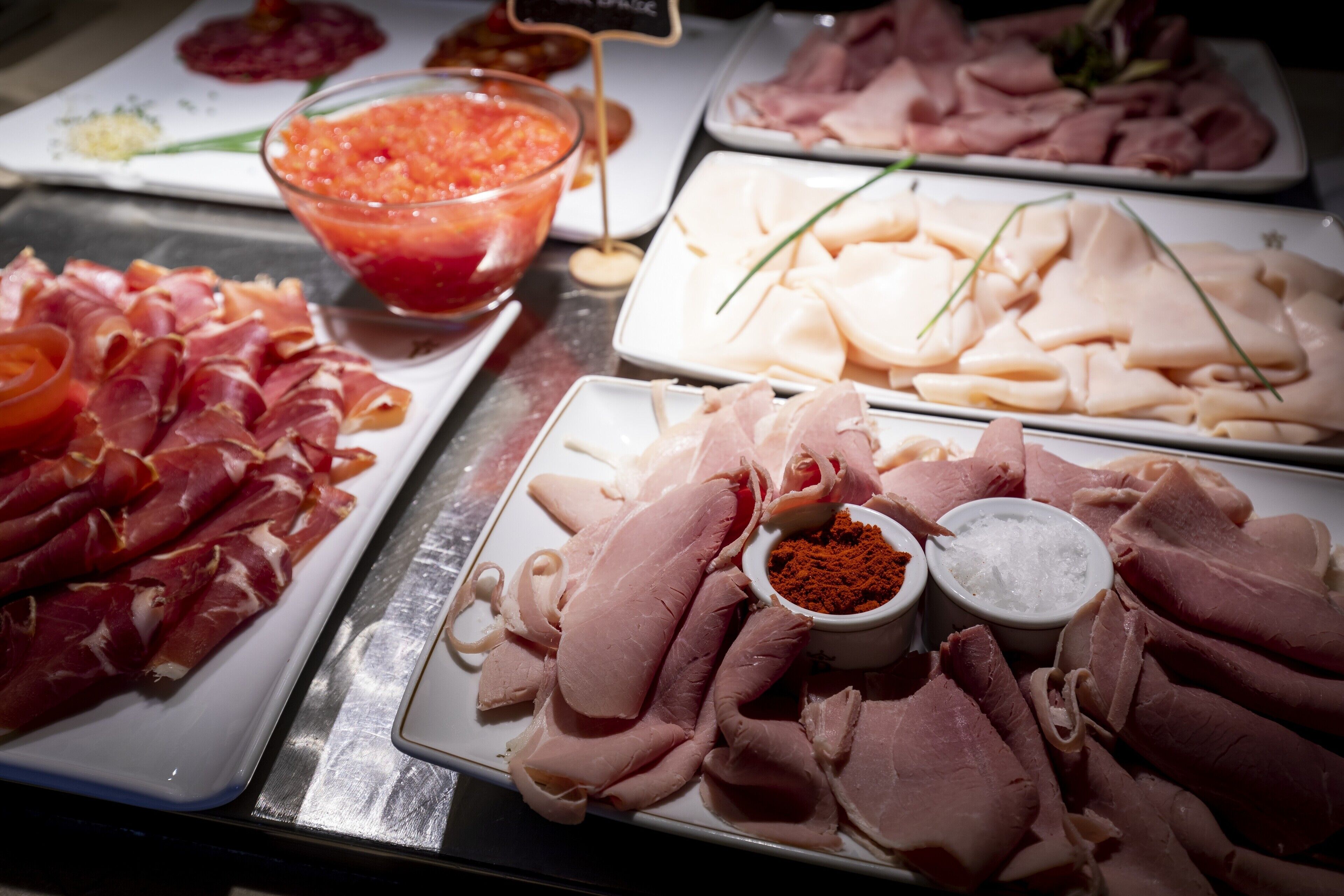 A buffet with various meats and condiments.