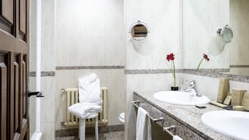 Un baño de hotel con un lavamanos blanco, un espejo, un perchero para toallas y un radiador.