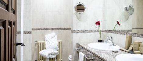 Un baño de hotel con un lavamanos blanco, un espejo, un perchero para toallas y un radiador.