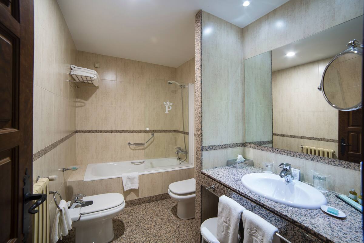A modern bathroom with a bathtub, toilet, sink, and large mirror.