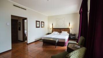 Habitación de hotel con cama doble, un banco, una silla, una mesita de noche y una lámpara de pared.