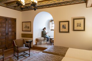 A room with wooden furniture, a stone bench, and framed pictures on the walls. - Parador De Vilalba (Villalba)
