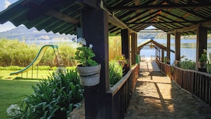 A covered outdoor area with a wooden deck, a slide, and a view of a lake and mountains.