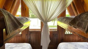 Un dormitorio acogedor en el desván con dos camas, vigas de madera y vistas por una ventana.