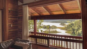 A wooden cabin with a large window overlooking a lake and forest.
