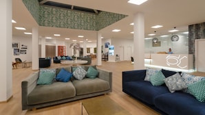 A spacious lobby with a grey sofa, a blue sofa, and a coffee table. - Apartamentos Santa Rosa (Teguise)