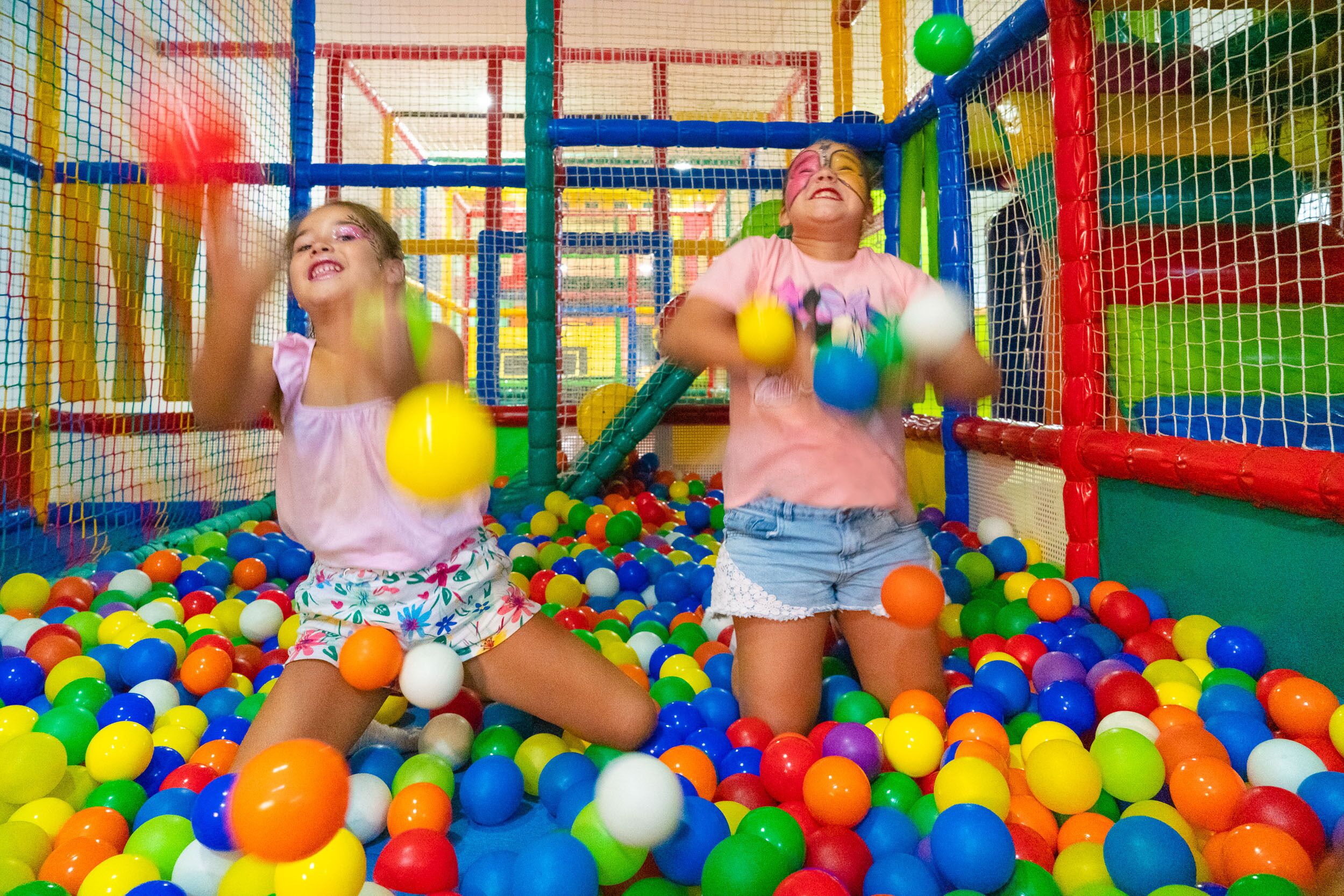 Zona de juegos con bolas de plástico de colores y una red divisoria.