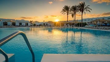 Una piscina cubierta, una piscina al aire libre, sombrillas