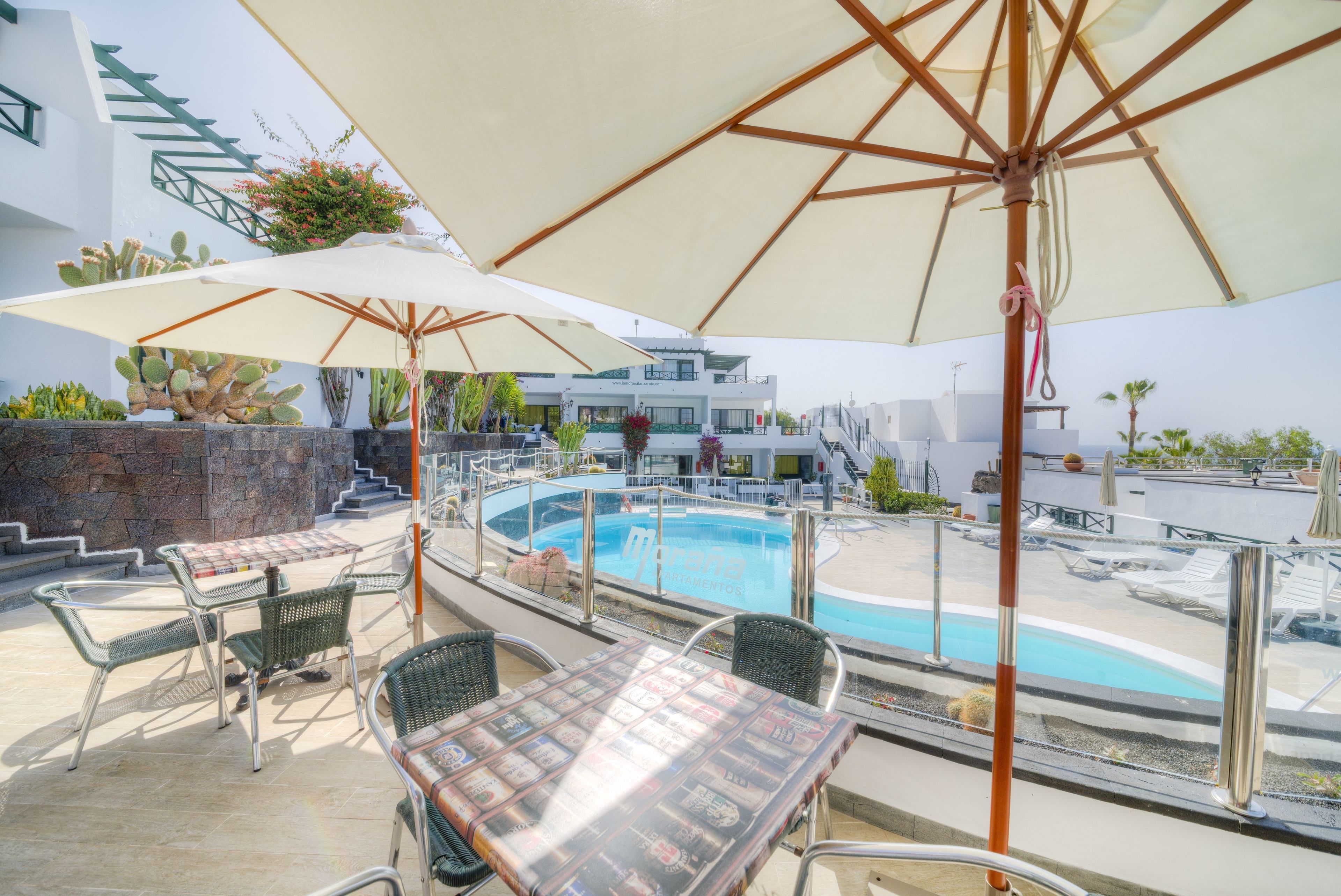 Zona de piscina con asientos exteriores y sombrillas.