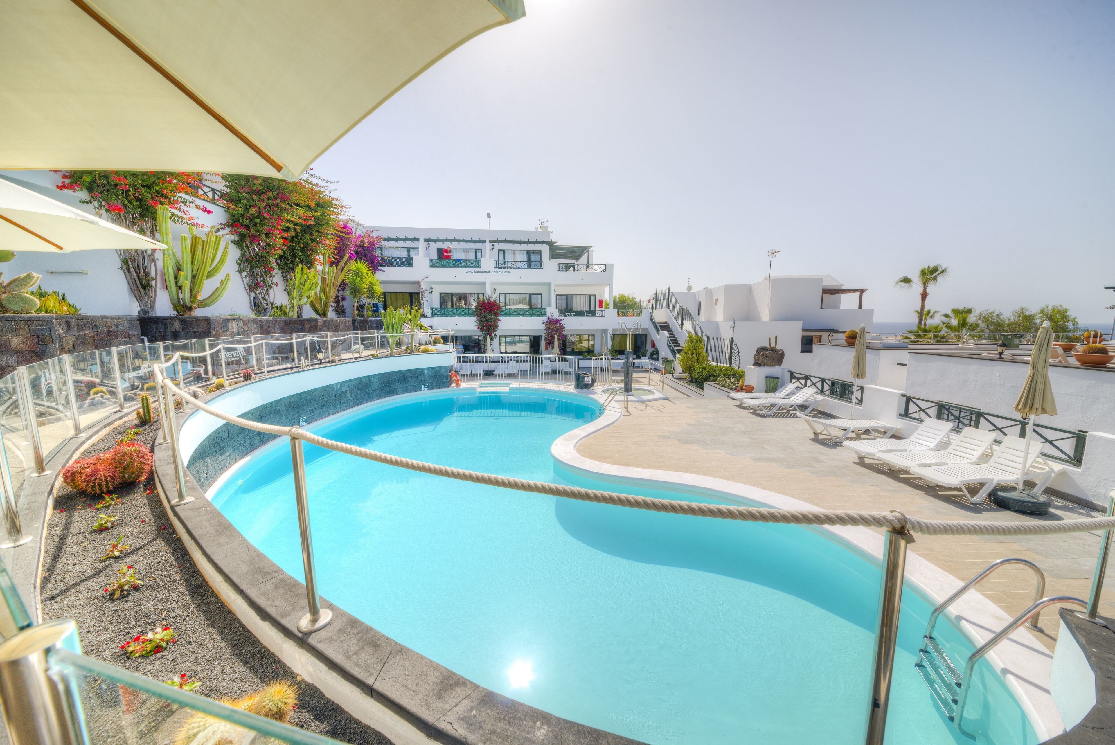 Una piscina sul tetto con vista libera sul mare, circondata da lettini e ombrelloni.