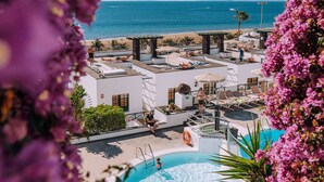 A rooftop pool area with a view of the sea, lounge chairs, and umbrellas. - Apartamentos La Moraña (Tías)