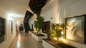 A corridor with potted plants, a staircase, and a fire extinguisher. - Apartamentos La Moraña (Tías)