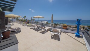 Una terrazza sul tetto con poltrone da relax, ombrelloni e vista sull'oceano.