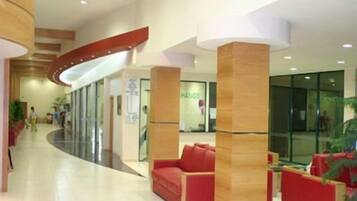 A modern lobby with a curved ceiling, red seating area, and glass doors leading to a hallway.