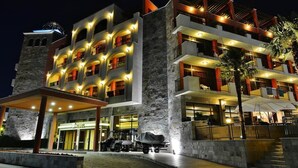 Ein mehrstöckiges Hotel mit einer Stein-Fassade, mehreren Balkonen und einem überdachten Eingangsbereich.