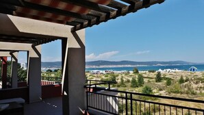 A balcony with a view of a coastal landscape, including a beach and distant mountains. - Nobel Ultra All Inclusive - Free Beach Access (Nessebar)