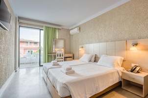 Quarto de hotel com duas camas, uma escrivaninha, uma cadeira, um telefone e vista para o exterior.