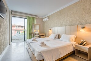 A hotel room with two beds, a desk, a chair, a phone, and a view of the outside. - Alkionis (Corfu)