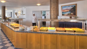 A buffet setup with various food items and a chef standing nearby. - Corali Hotel (Kos)