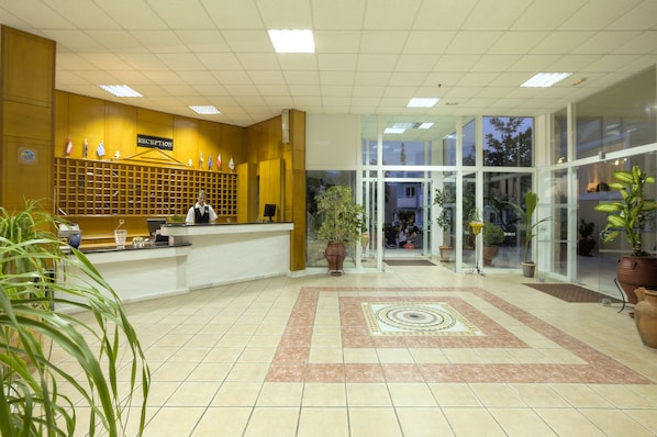 A reception area with a reception desk, a sign indicating 'RECEPTION', and potted plants. - Corali Hotel (Kos)