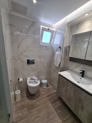 A modern bathroom with a toilet, sink, and shower. - Corali Hotel (Kos)