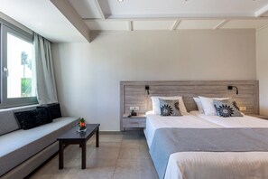 A modern bedroom with a sofa, a bed, a bedside table, and a nightstand. - Palladium Hotel (KOS)