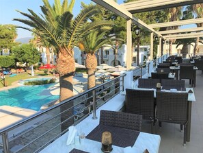 A poolside area with wicker furniture and a view of a swimming pool. - Palladium Hotel (KOS)