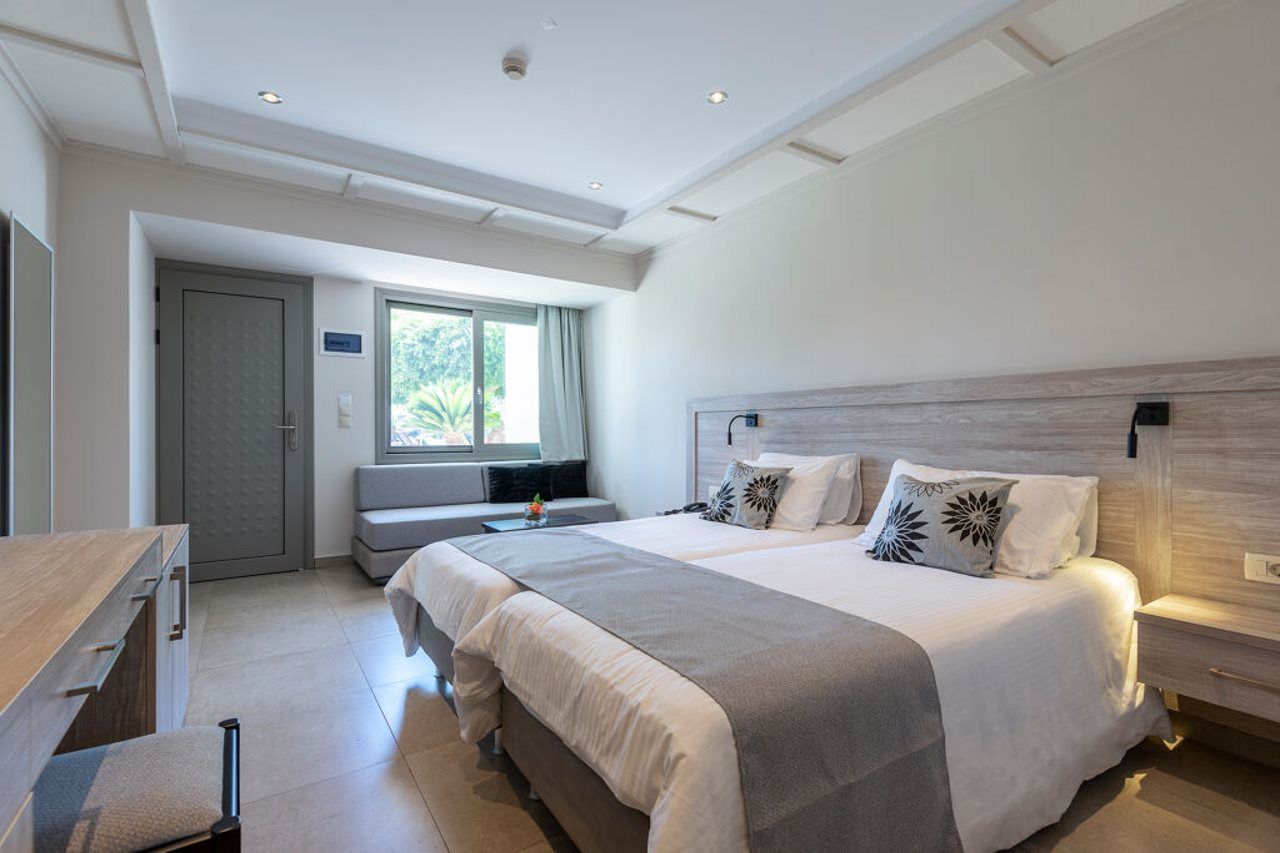A modern bedroom with a large bed, bedside tables, a desk, and a window.
