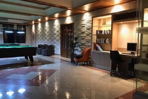 Un interior moderno con mesa de billar, una zona de estar con una silla y un escritorio con computadora.