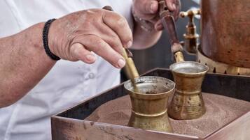 Una persona operando una cafetera con un recipiente de bronce y un contenedor metálico.