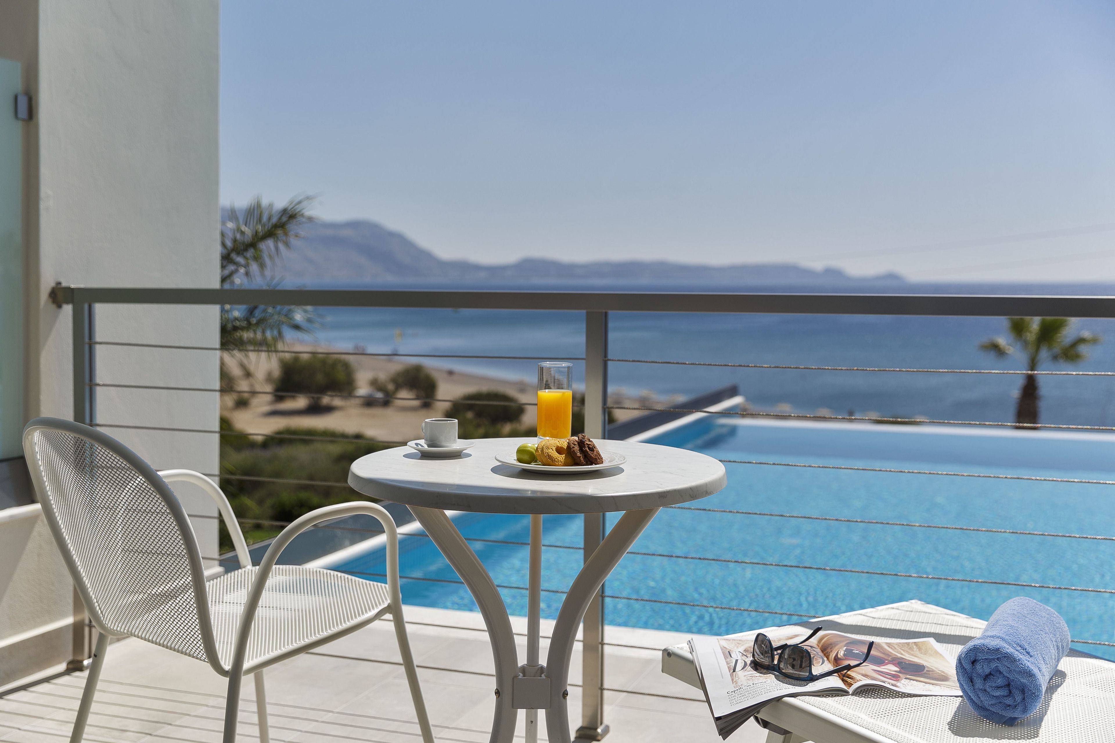A balcony with a table, chairs, a newspaper, and a towel.
