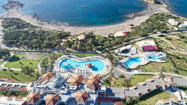 Vista aérea de um resort com uma grande piscina, praia e vegetação exuberante.