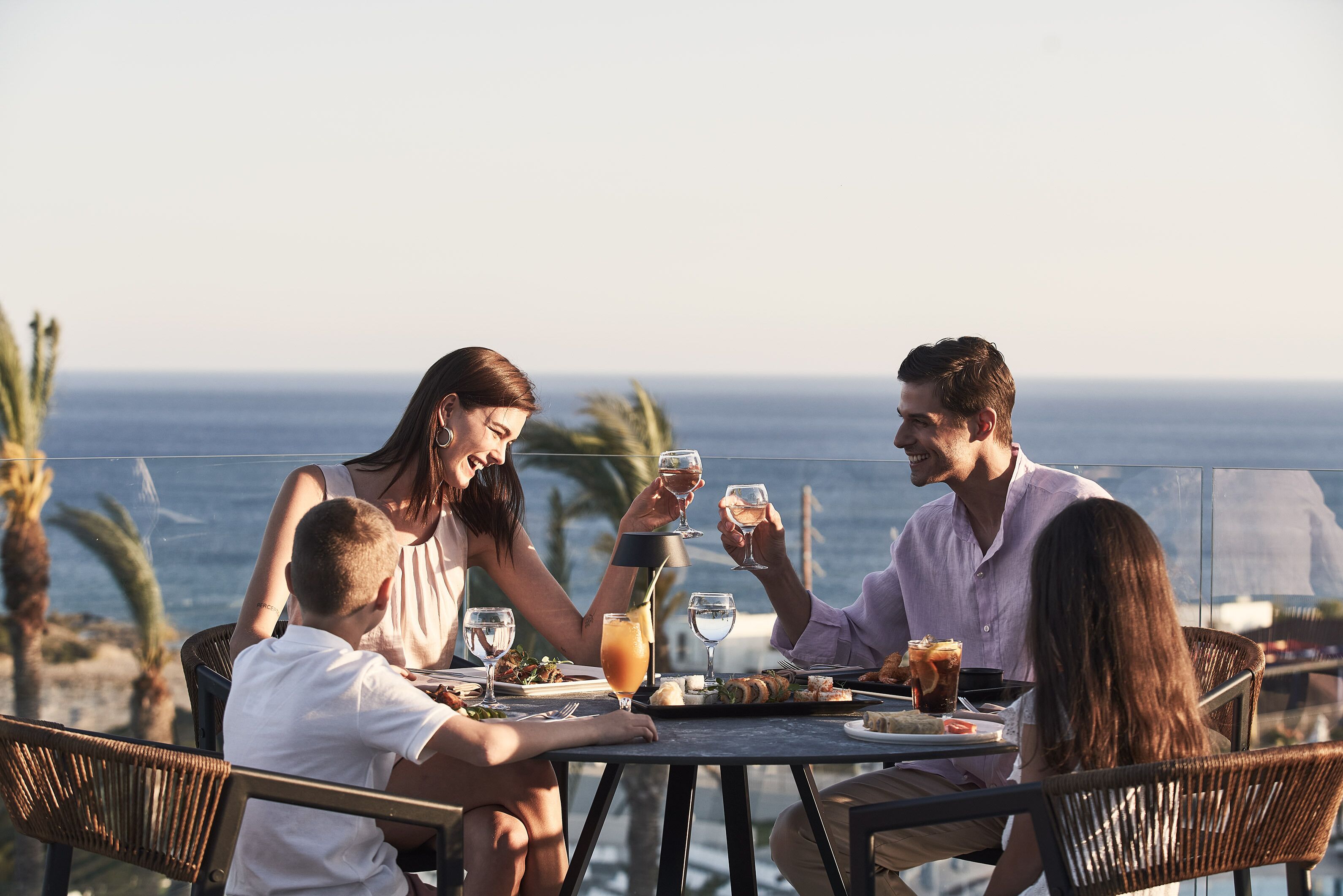 Eine Gruppe von Menschen speist an einem Tisch im Freien mit Blick auf das Meer.