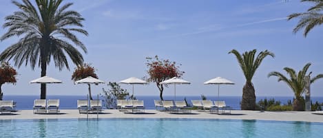 Una piscina cubierta, una piscina al aire libre, sombrillas, tumbonas