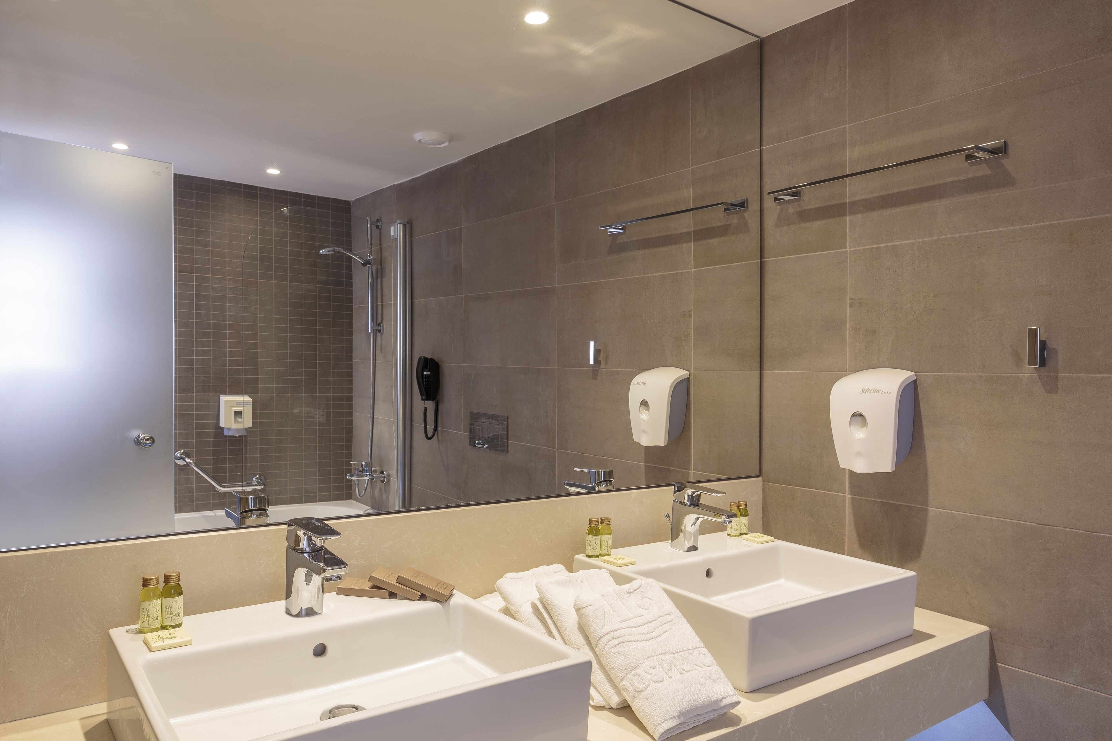 A modern bathroom with two sinks, a shower, and a large mirror.