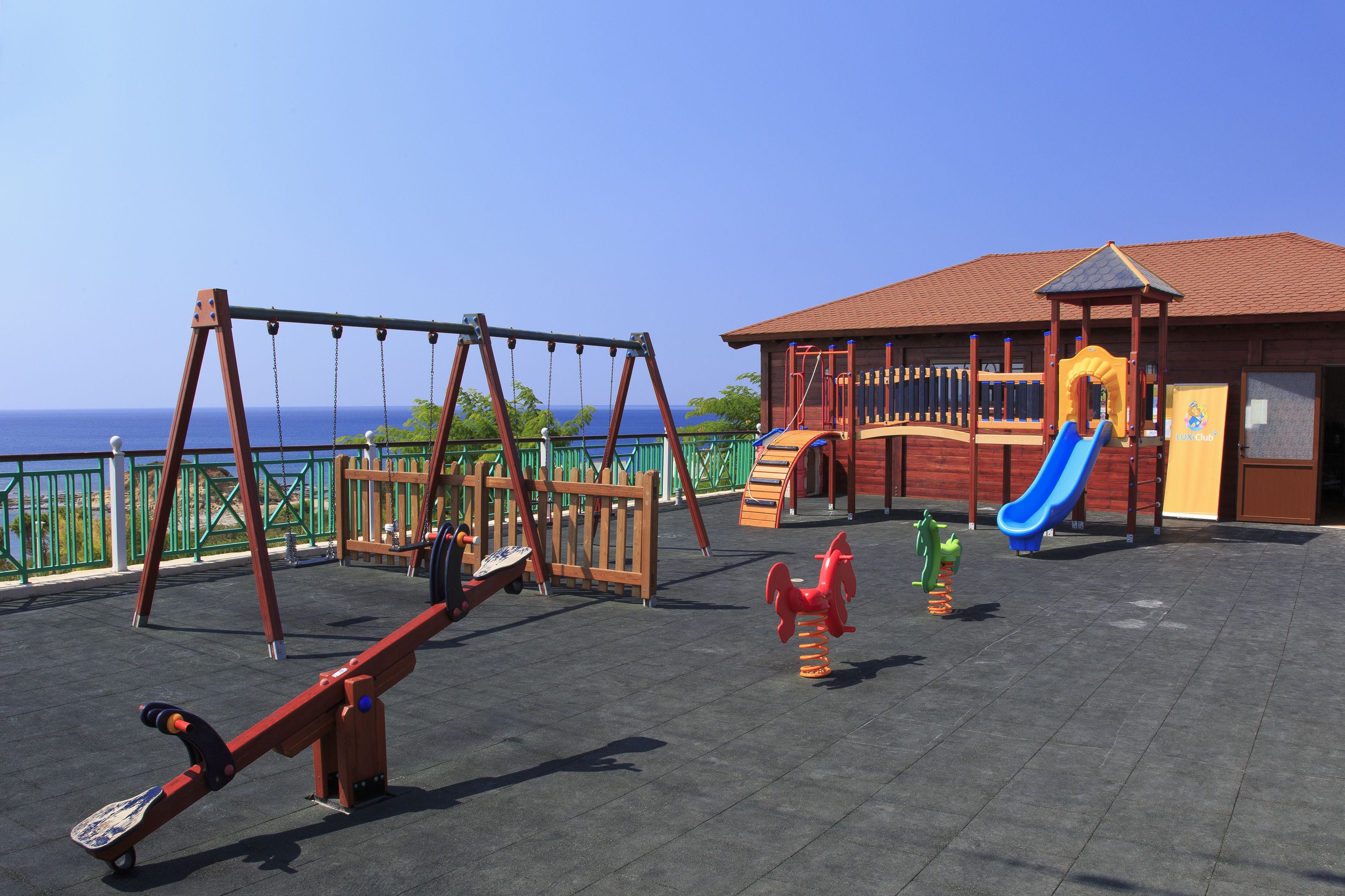 Ein Spielplatz mit Schaukeln, einer Rutsche und einer Kletterkonstruktion.
