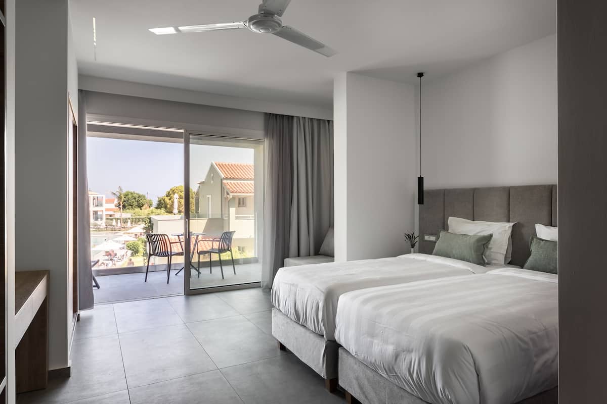 Ein modernes Hotelzimmer mit einem großen Bett, einem Deckenventilator und Blick ins Freie.