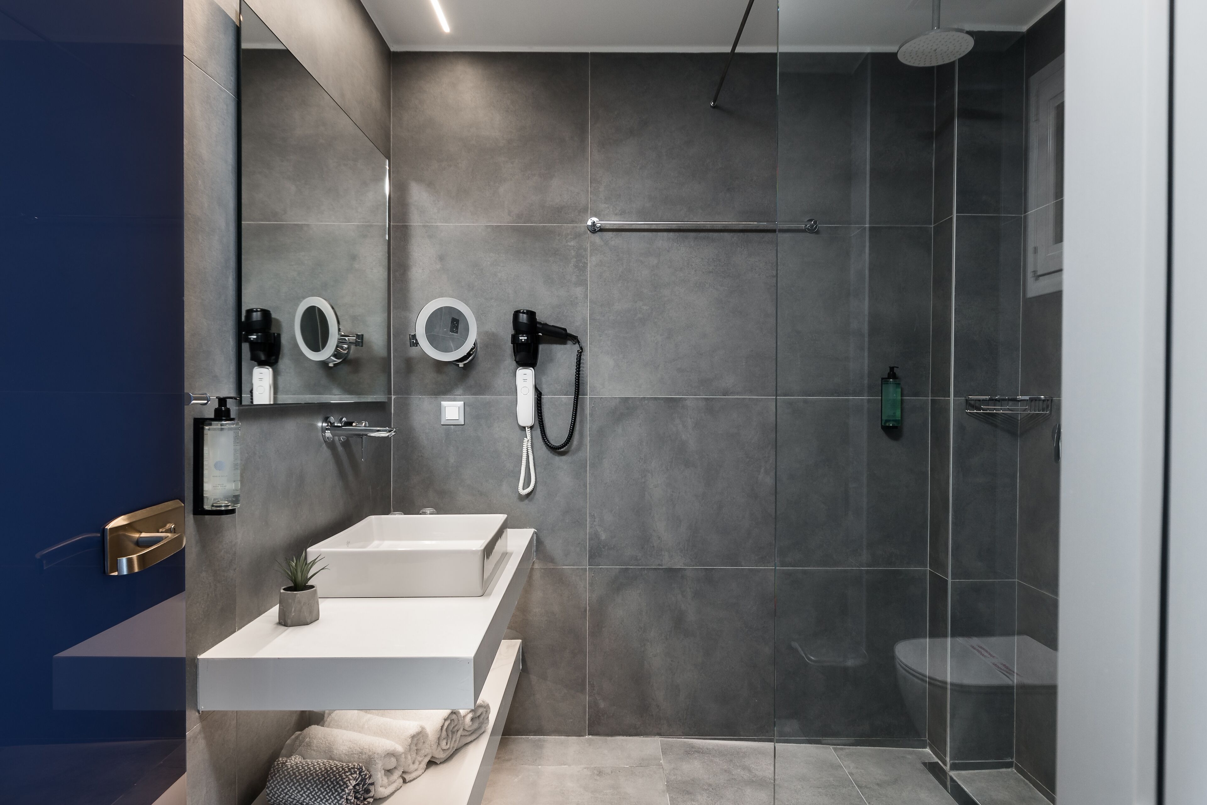 A modern bathroom with a glass-enclosed shower, a vanity with a sink and mirror, and a towel rack.