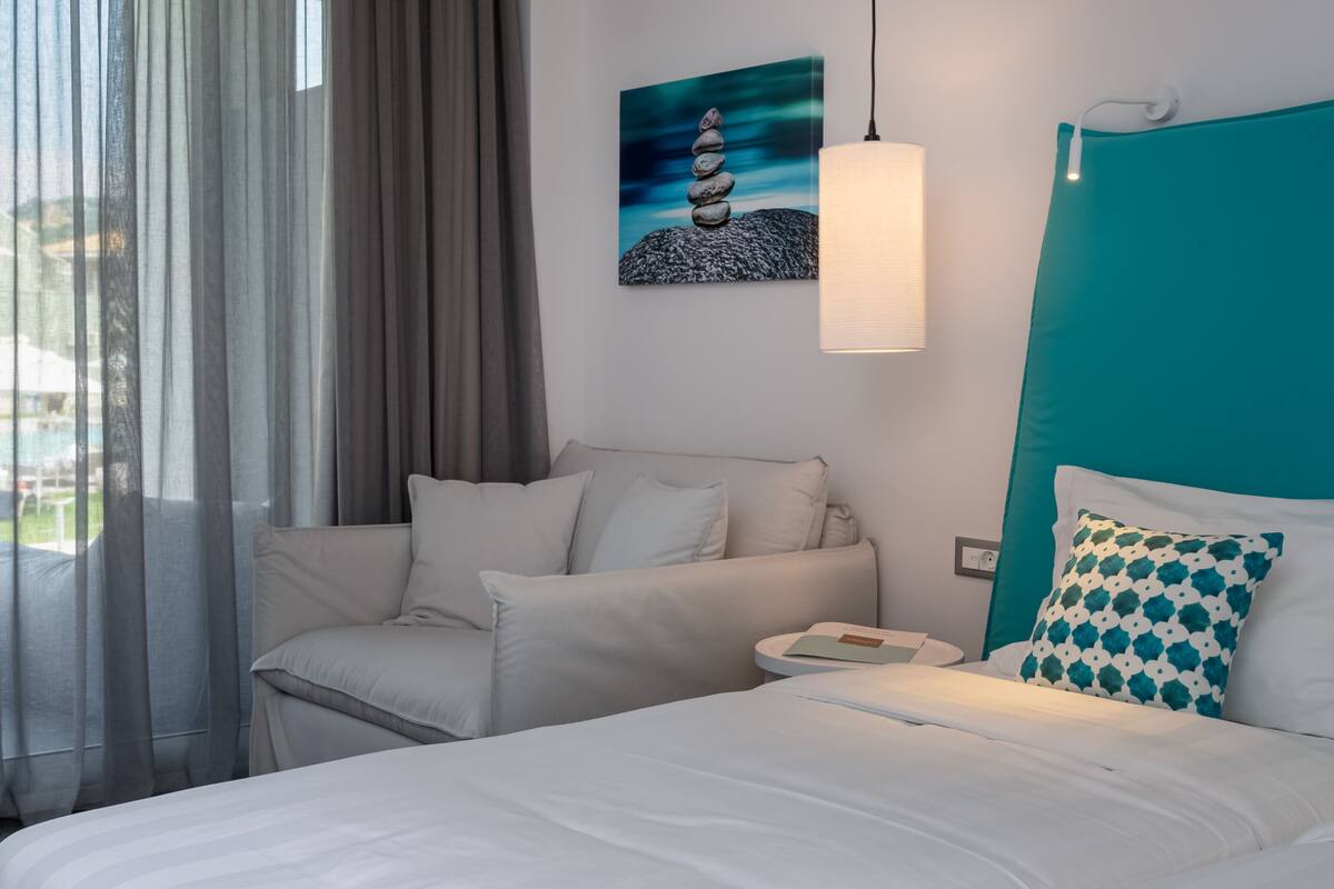 Una habitación de hotel moderna con cama, sofá, escritorio y un cuadro en la pared.