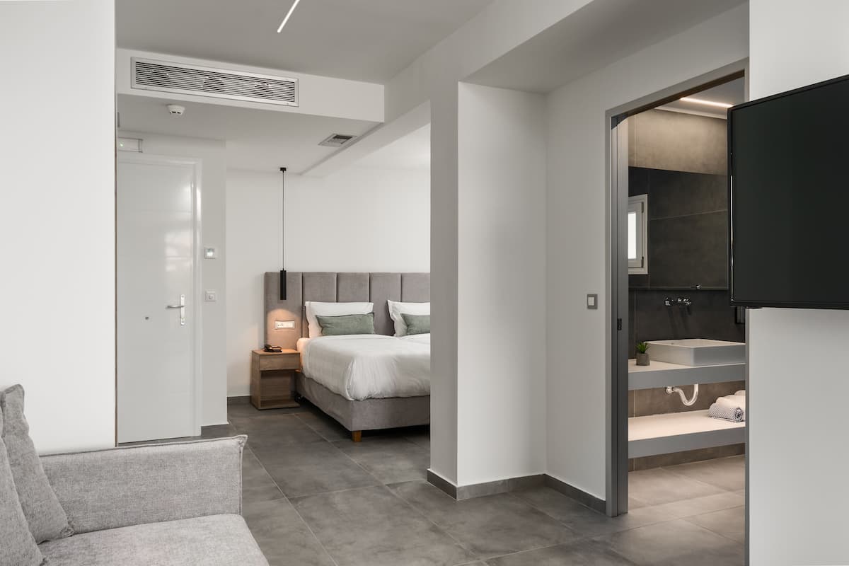 Ein modernes Hotelzimmer mit Bett, Nachttisch, Lampe und integriertem Fernseher.